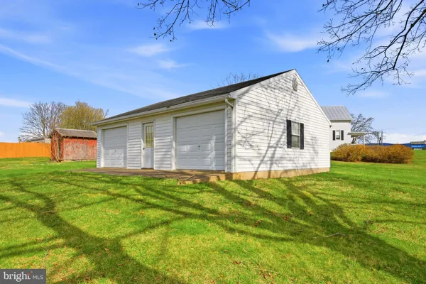 a backyard of a house with plants and large tree