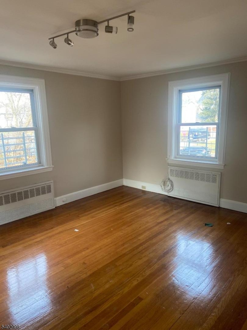 725 Elizabeth Avenue, Unit 2 Newark, NJ 07112 - Photo 2 of 8 an empty room with wooden floor and windows