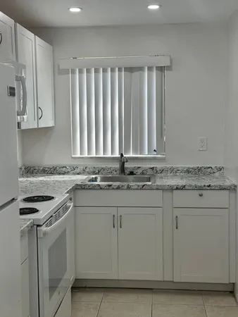 a kitchen with granite countertop white cabinets and white appliances