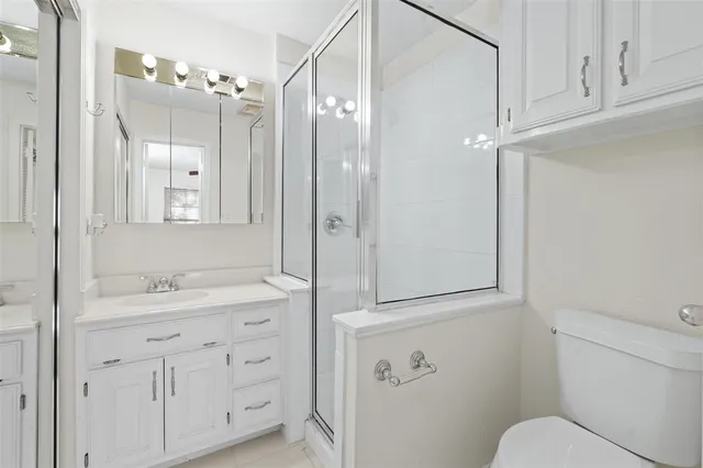 a bathroom with a shower sink vanity mirror and toilet