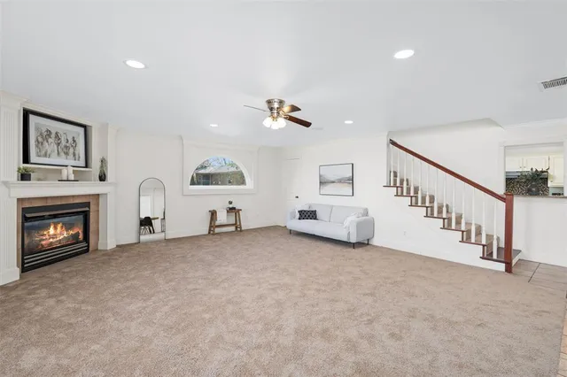 a view of an empty room with fireplace stairs and a window