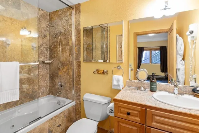 a bathroom with a granite countertop sink a toilet a mirror and shower