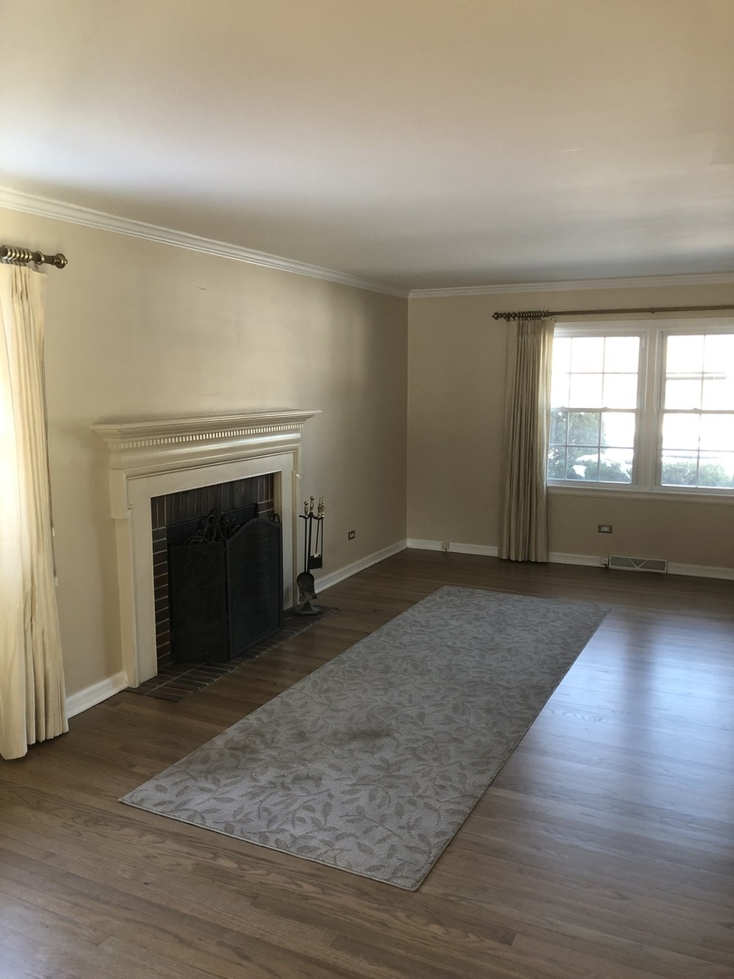1577 Banbury Road Inverness, IL 60067 - Photo 3 of 8 an empty room with wooden floor fireplace and windows