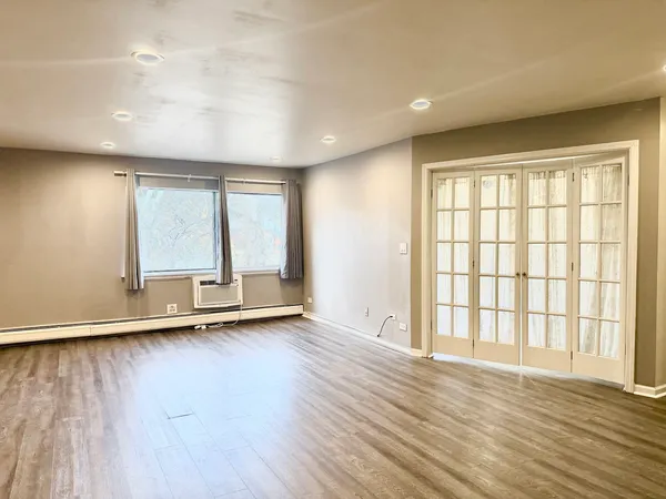 an empty room with wooden floor and windows
