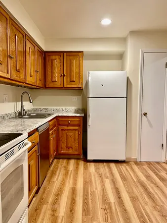 a kitchen with stainless steel appliances granite countertop a refrigerator a sink dishwasher and white cabinets with wooden floor