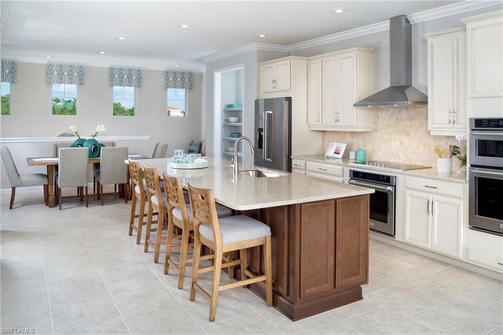 4677 Arboretum Circle, Unit 202 Naples, FL 34112 - Photo 6 of 15 a kitchen with stainless steel appliances a sink a stove a refrigerator cabinets and chairs
