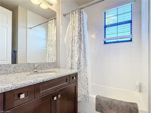 a bathroom with a granite countertop sink a mirror and a bathtub