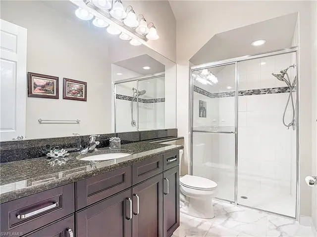 a bathroom with a granite countertop sink toilet a mirror and shower