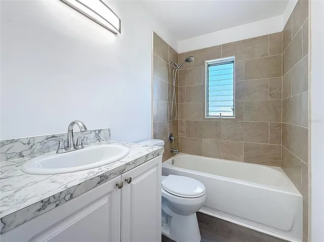 a bathroom with a granite countertop sink a toilet and bathtub