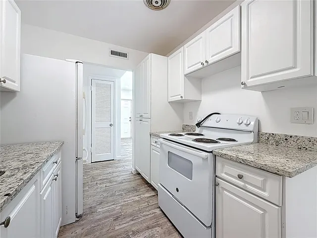 a kitchen with granite countertop cabinets stainless steel appliances and wooden floor