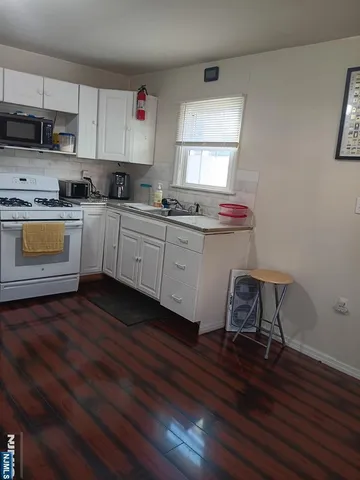 a kitchen with a sink a stove cabinets and wooden floor