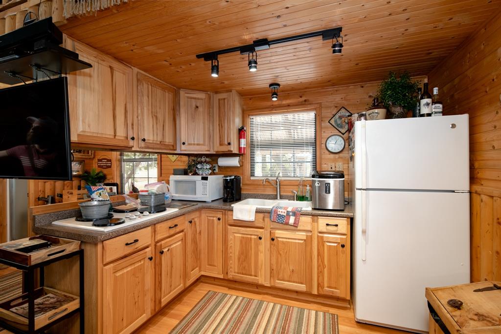 15055 County Road 306 Cisco, TX 76437 - Photo 11 of 40 a kitchen with a refrigerator a stove a sink dishwasher and wooden cabinets
