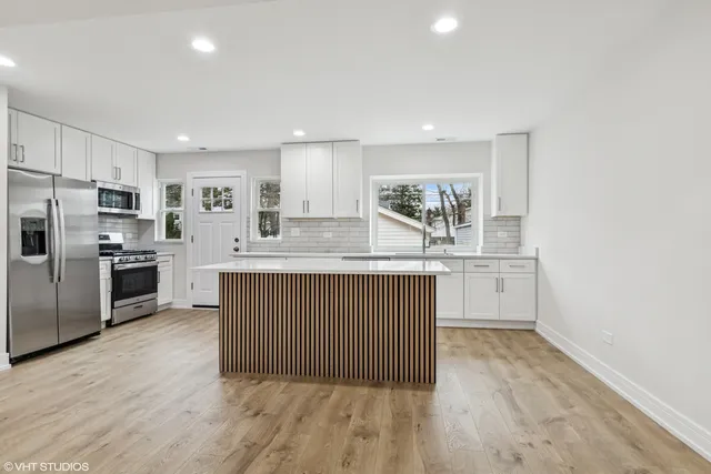 a kitchen with kitchen island granite countertop a sink and refrigerator