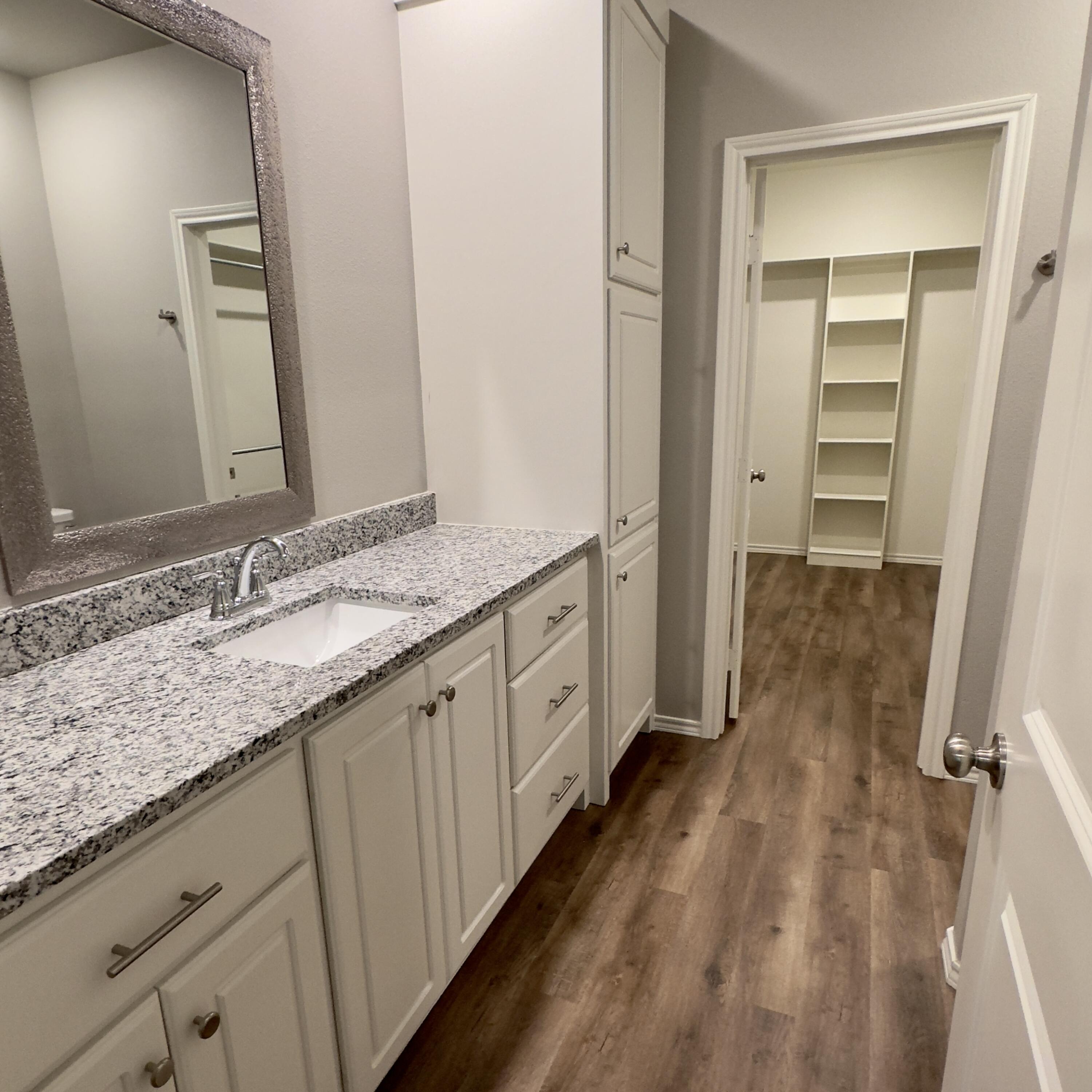 1225 Preston Trail, Unit A Wolfforth, TX 79382 - Photo 13 of 16 a spacious bathroom with a granite countertop sink and a mirror