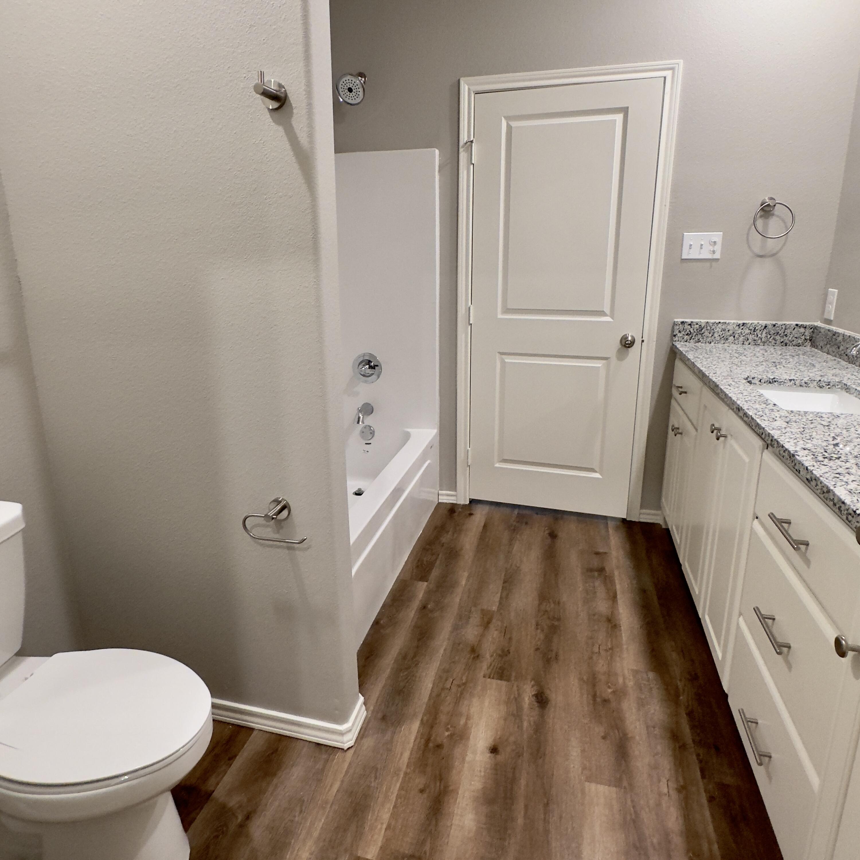 1225 Preston Trail, Unit A Wolfforth, TX 79382 - Photo 15 of 16 a bathroom with a granite countertop shower toilet and sink