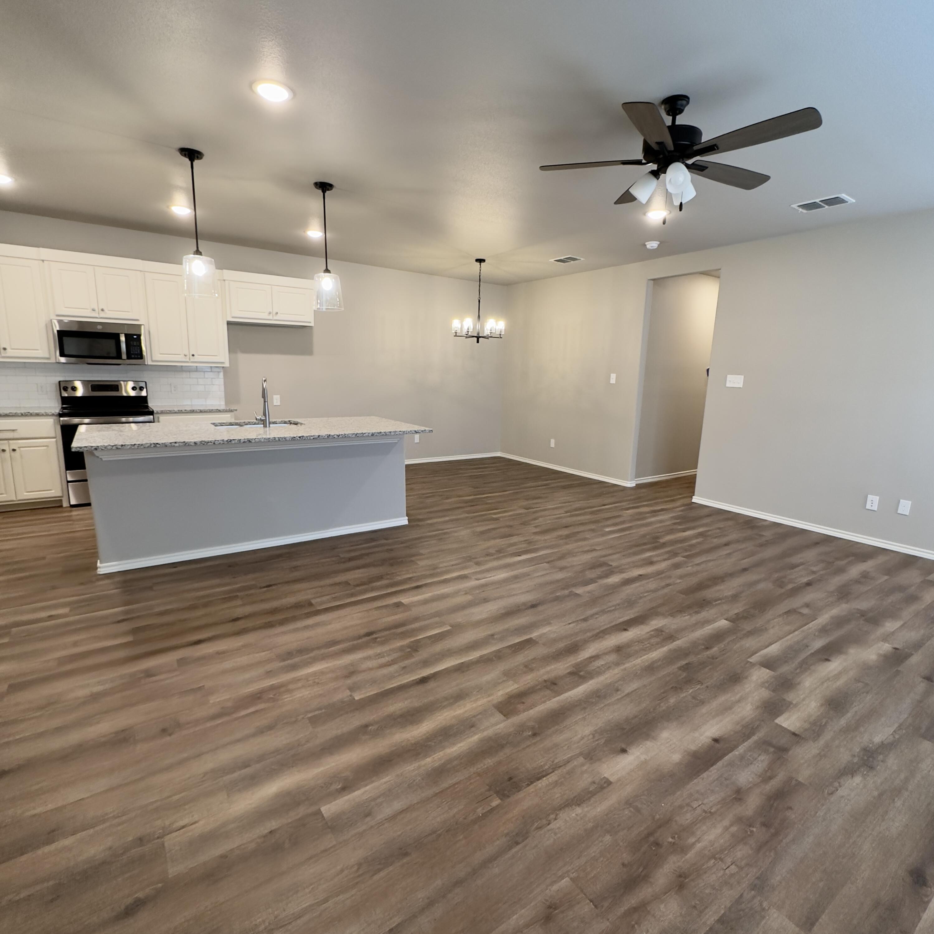 1225 Preston Trail, Unit A Wolfforth, TX 79382 - Photo 2 of 16 an empty room with wooden floor and a ceiling fan