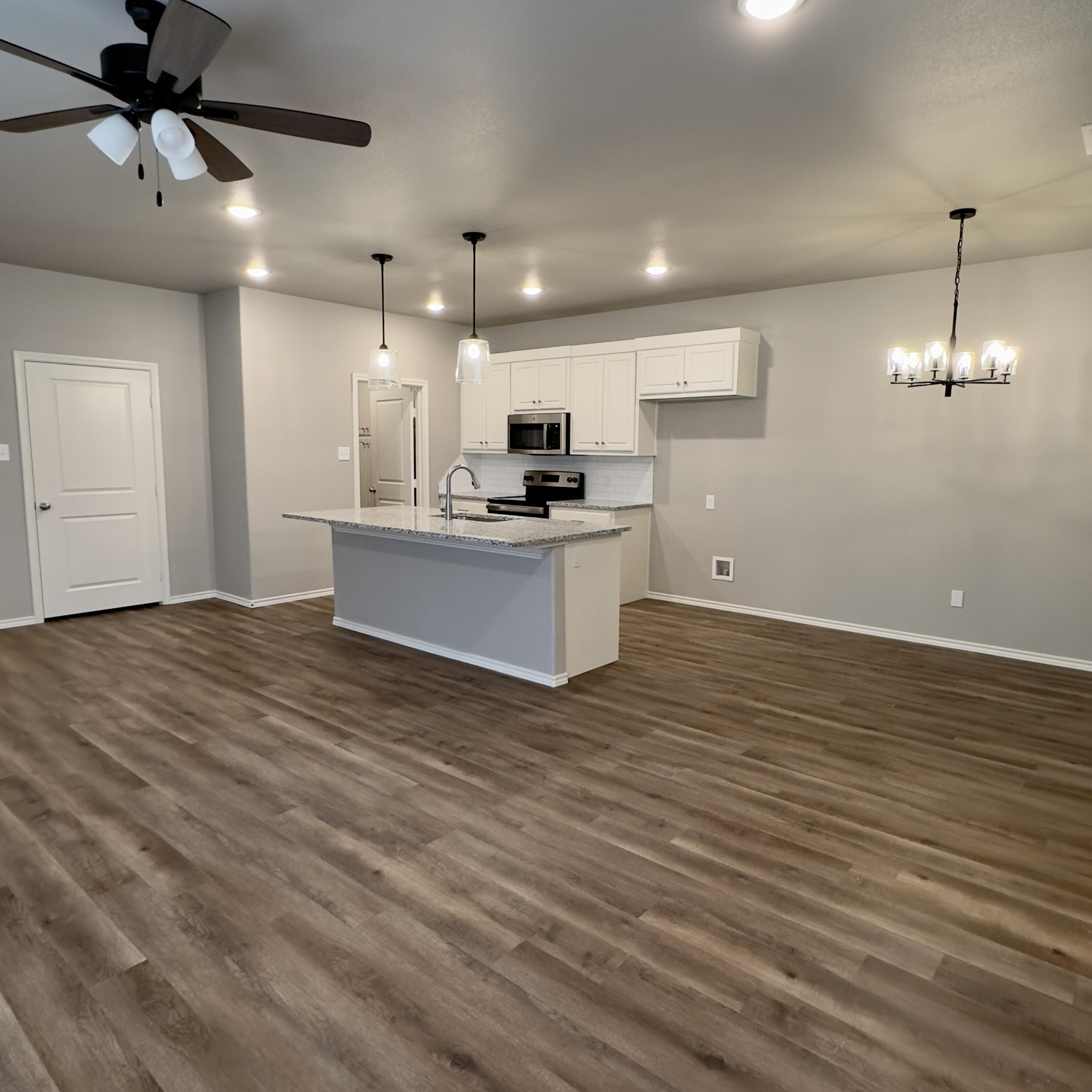 1225 Preston Trail, Unit A Wolfforth, TX 79382 - Photo 3 of 16 a view of kitchen and empty room with wooden floor