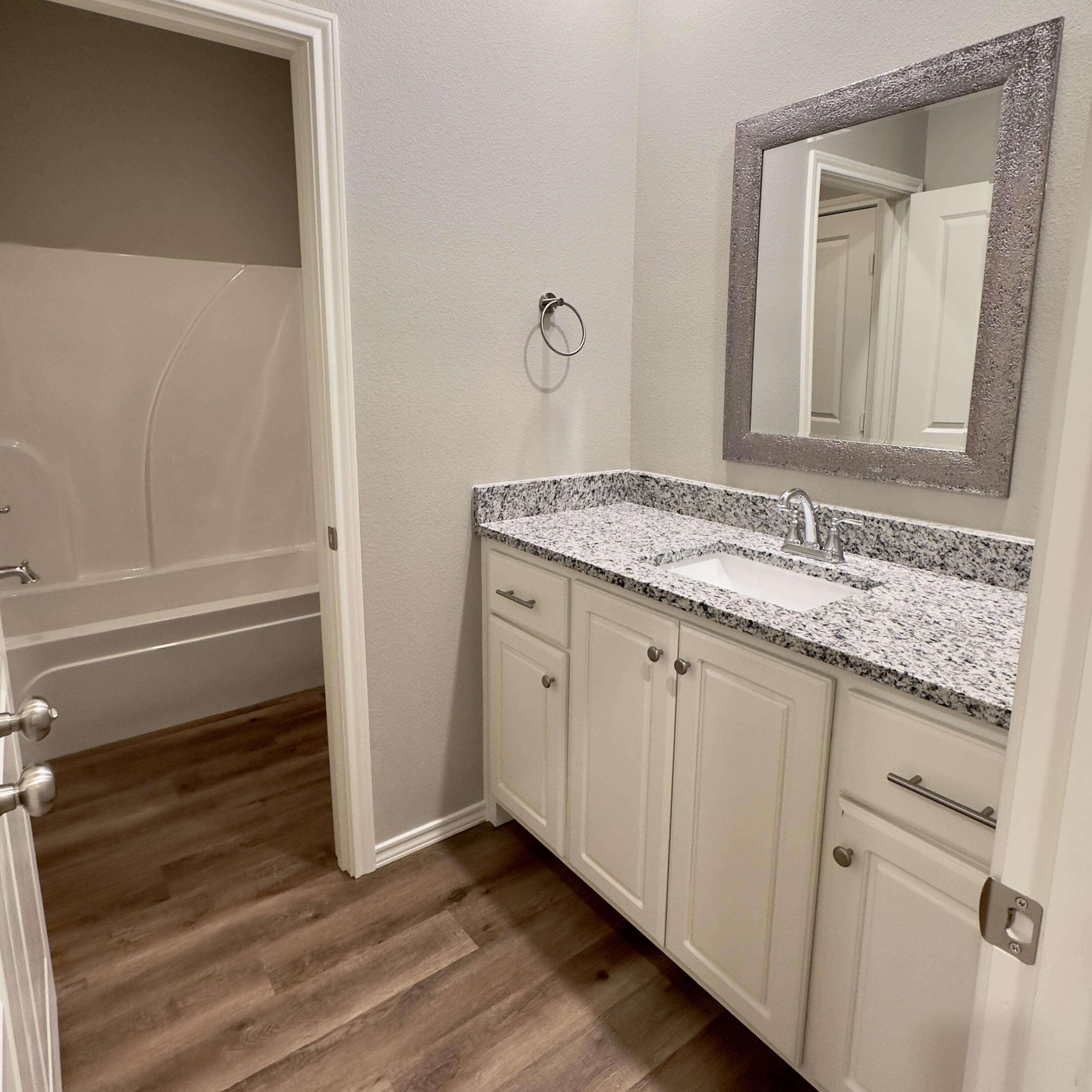 1225 Preston Trail, Unit A Wolfforth, TX 79382 - Photo 7 of 16 a bathroom with a granite countertop sink and a mirror