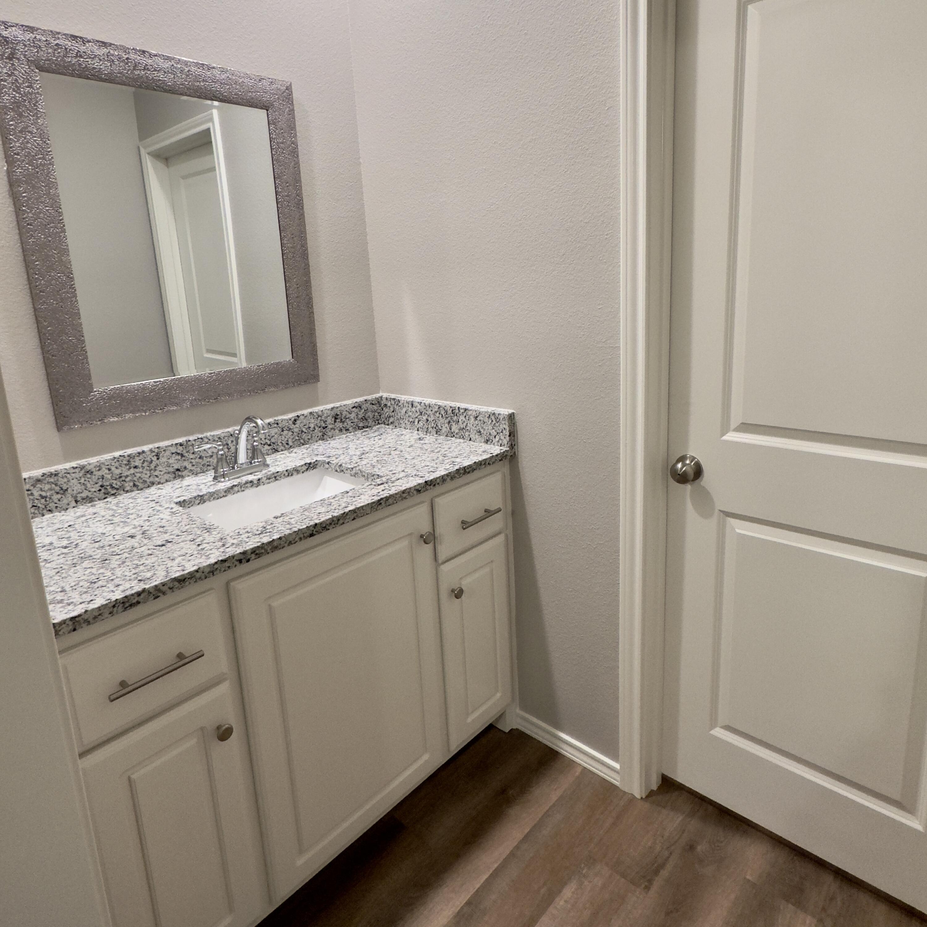 1225 Preston Trail, Unit A Wolfforth, TX 79382 - Photo 10 of 16 a bathroom with a granite countertop sink and a mirror