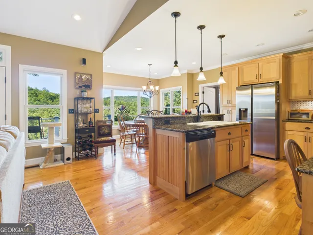 a kitchen with a counter top space a sink appliances and a living room view