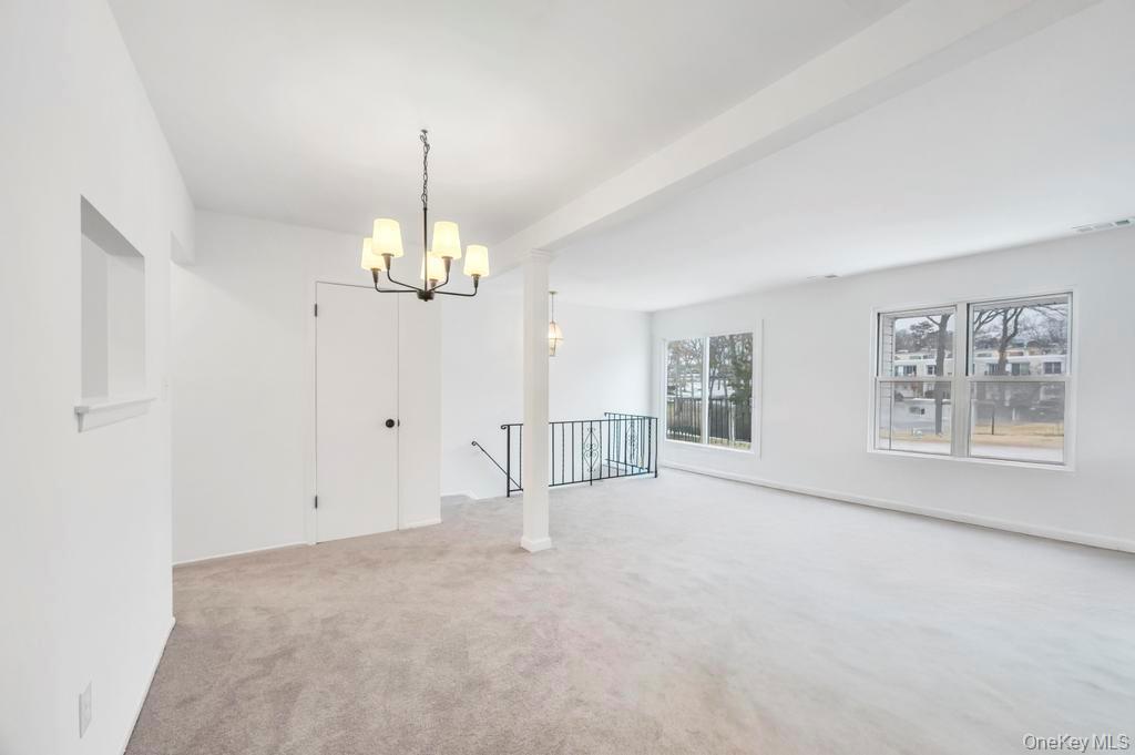 85 Rocky Point Yaphank Road, Unit 168 Rocky Point, NY 11778 - Photo 10 of 32 an empty room with chandelier fan and windows