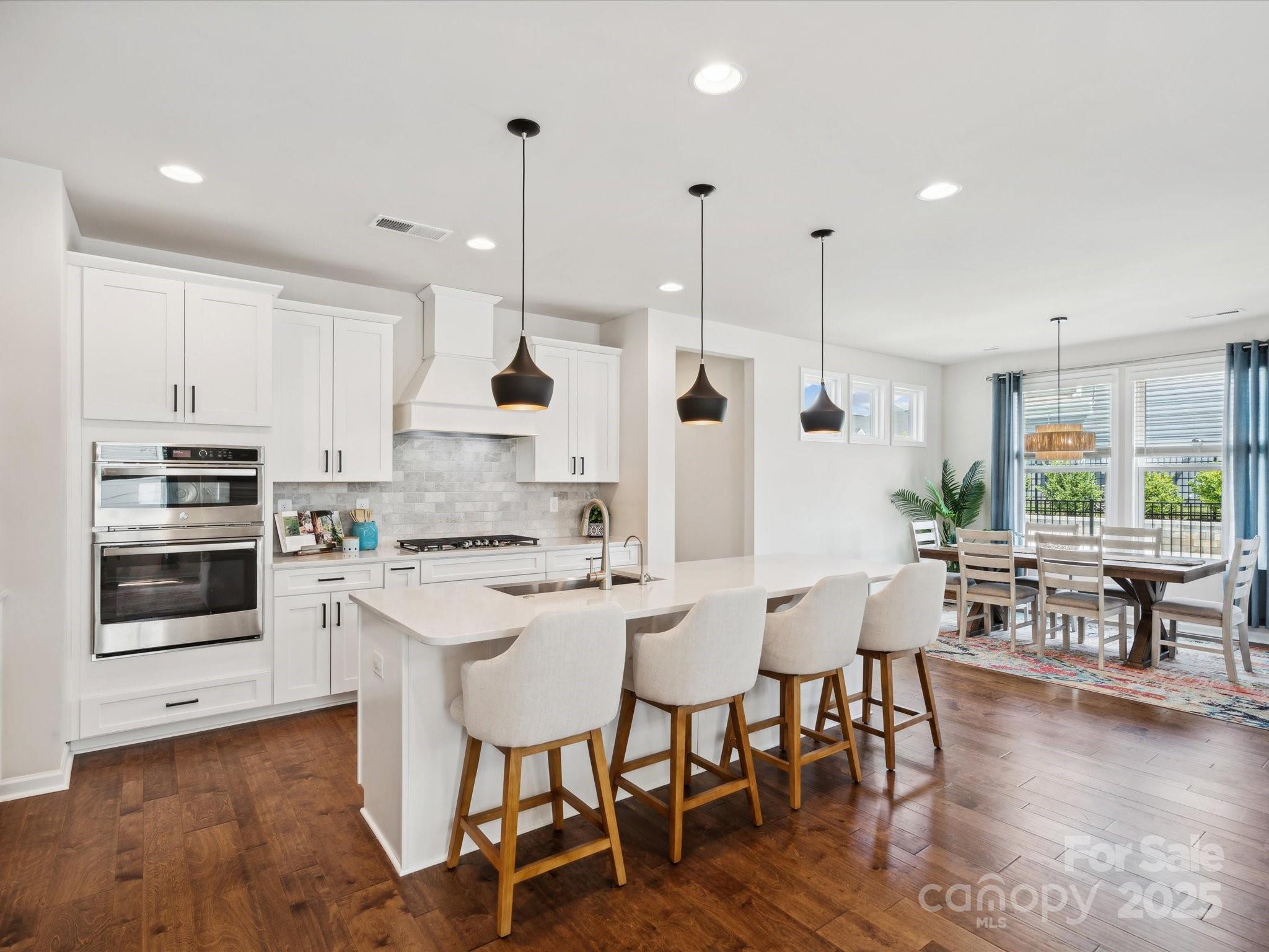 924 Stebbins Drive Fort Mill, SC 29715 - Photo 13 of 48 a kitchen with stainless steel appliances kitchen island granite countertop a stove a sink a dining table and chairs with wooden floor
