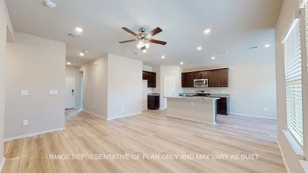 a view of an empty room with kitchen and microwave