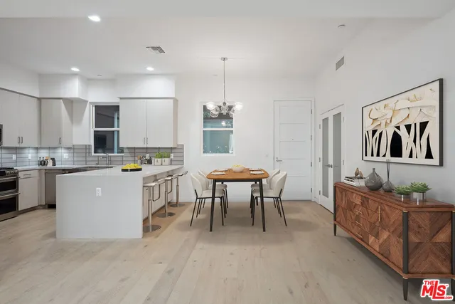 a living room with couches chairs and kitchen view with wooden floor