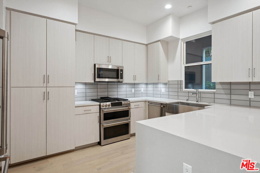 1746 Garfield Place, Unit 102 Los Angeles, CA 90028 - Photo 6 of 32 a kitchen with stainless steel appliances a stove sink and microwave