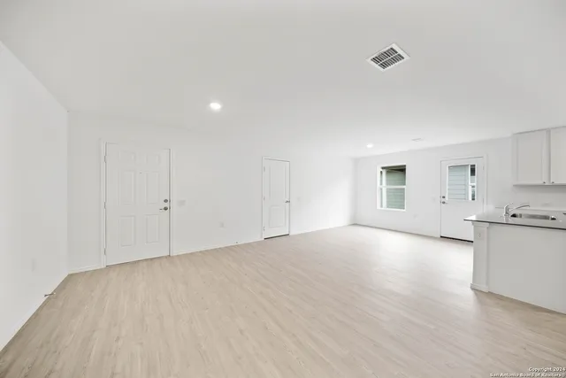 a view of a kitchen with a sink and dishwasher a stove top oven with wooden floor