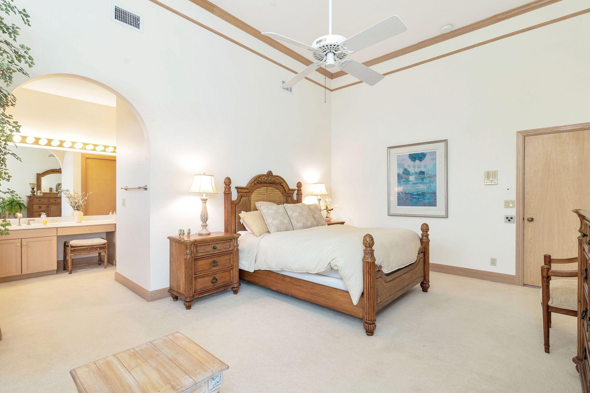 3330 Bridgegate Drive Jupiter, FL 33477 - Photo 25 of 39 a spacious bedroom with a bed a table and painting