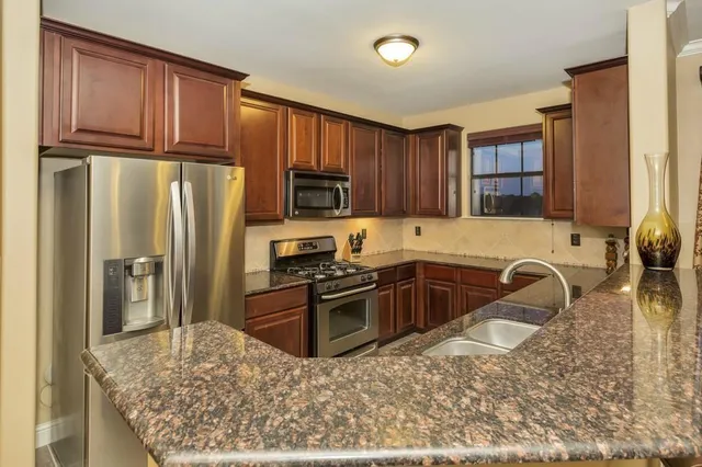 a kitchen with granite countertop wooden cabinets a refrigerator and a sink