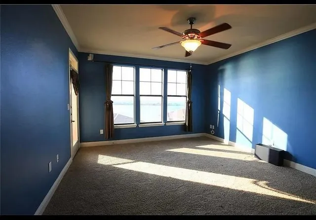 a view of an empty room with window and a kitchen