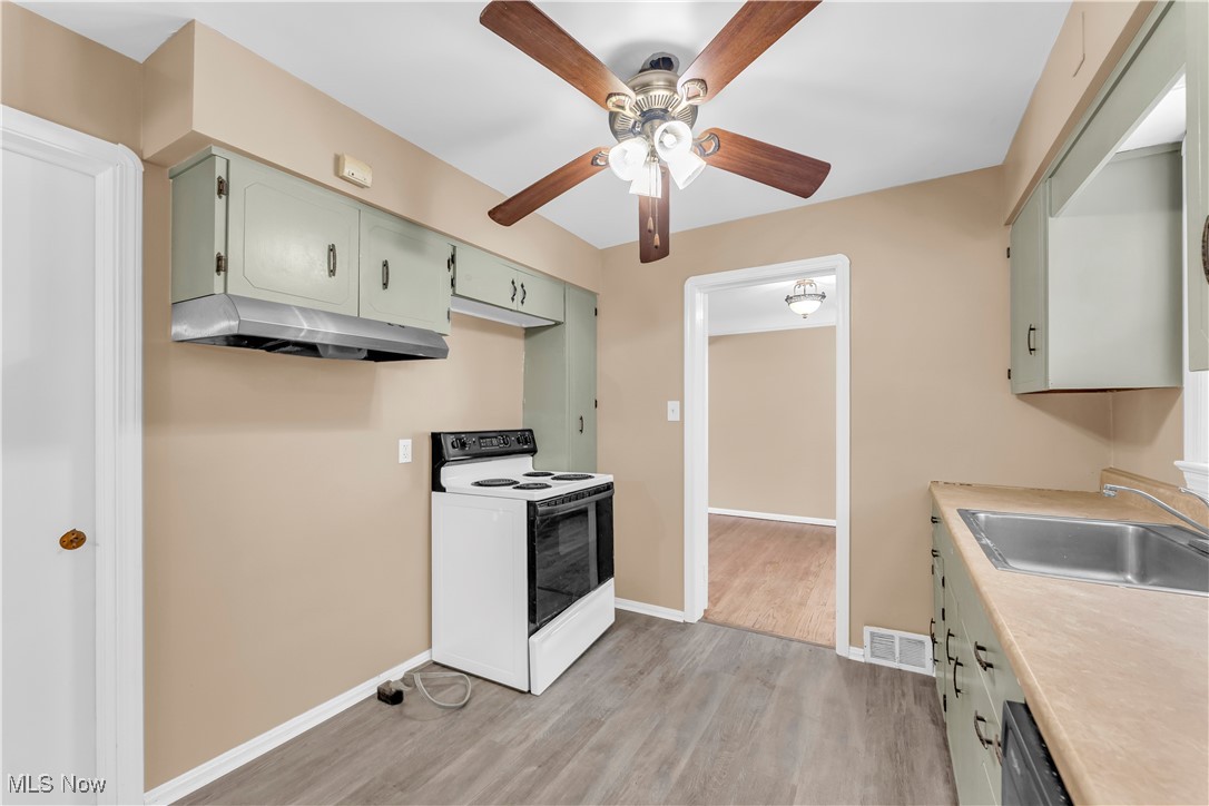 4693 Liberty Road South Euclid, OH 44121 - Photo 13 of 33 Kitchen featuring green cabinets, white electric stove, light countertops, light wood-style floors, and under cabinet range hood