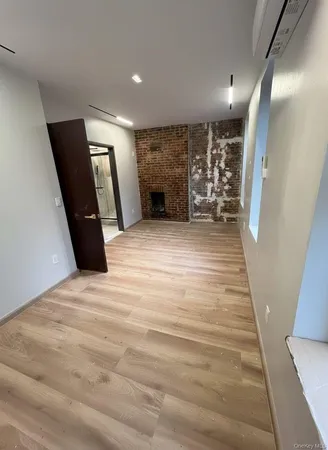 a view of an empty room with wooden floor and a fireplace