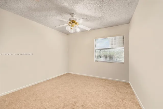 an empty room with a chandelier fan and windows
