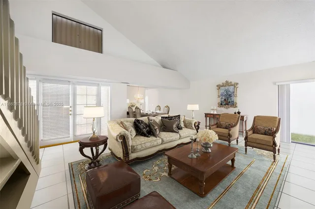 a living room with furniture a rug potted plant and a large window