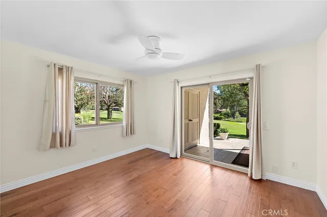 an empty room with windows and chandelier fan