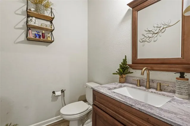 a bathroom with a granite countertop toilet and a sink
