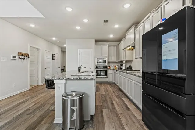 a kitchen with kitchen island white cabinets appliances and wooden floor