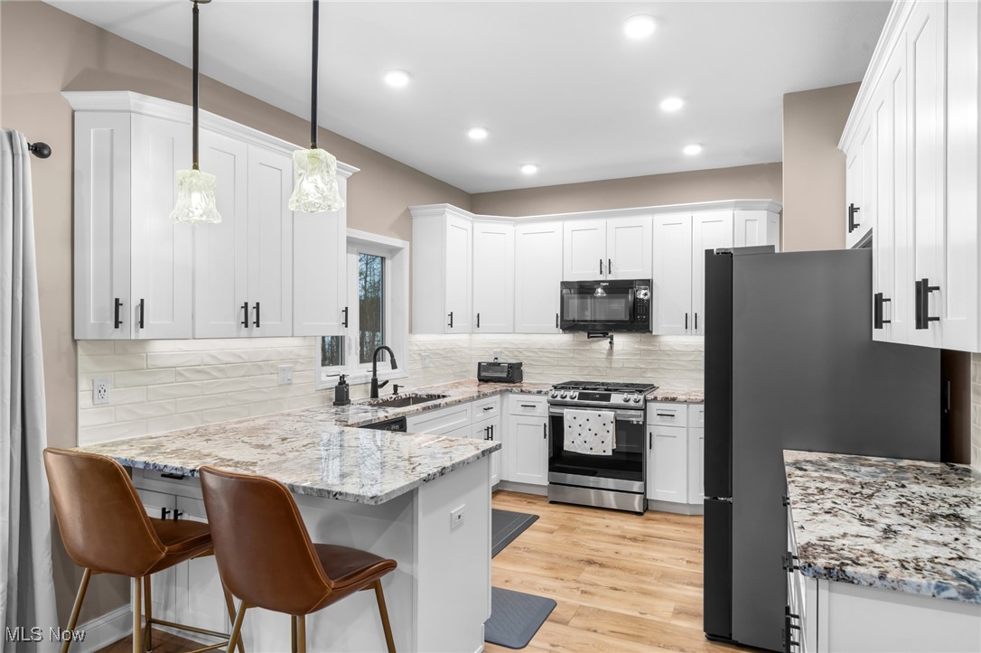 39600 Aurora Road Solon, OH 44139 - Photo 23 of 49 Kitchen with light stone counters, appliances with stainless steel finishes, white cabinets, and a kitchen bar