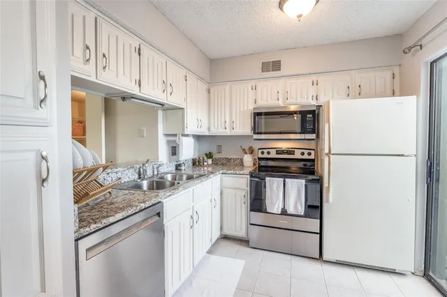 a kitchen with granite countertop a refrigerator stove and microwave