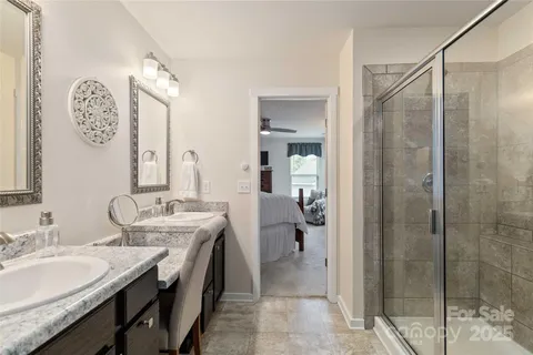 a spacious bathroom with a granite countertop sink a mirror and a shower