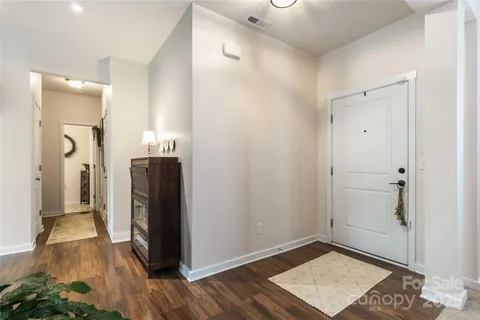 a view of a hallway with wooden floor and a bathroom
