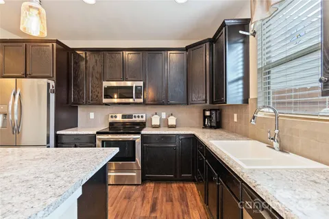 a kitchen with stainless steel appliances granite countertop a sink stove microwave and refrigerator