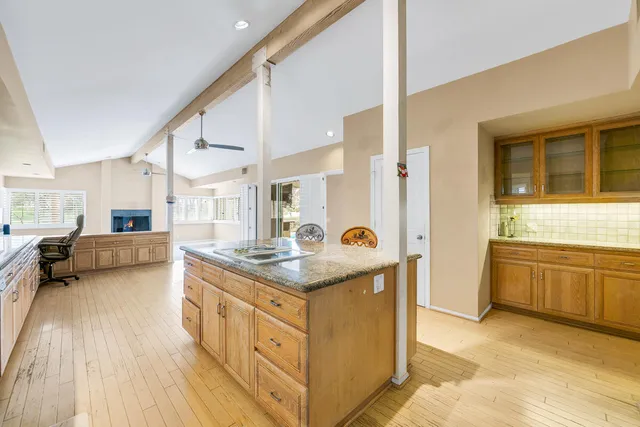 a kitchen with stainless steel appliances granite countertop a stove a sink dishwasher a refrigerator and white cabinets with wooden floor