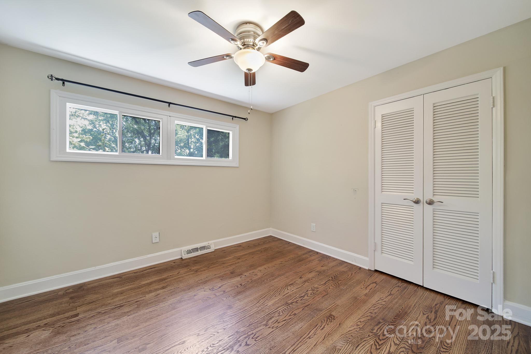 7424 Watercrest Road Charlotte, NC 28210 - Photo 12 of 32 a view of an empty room with wooden floor and a ceiling fan