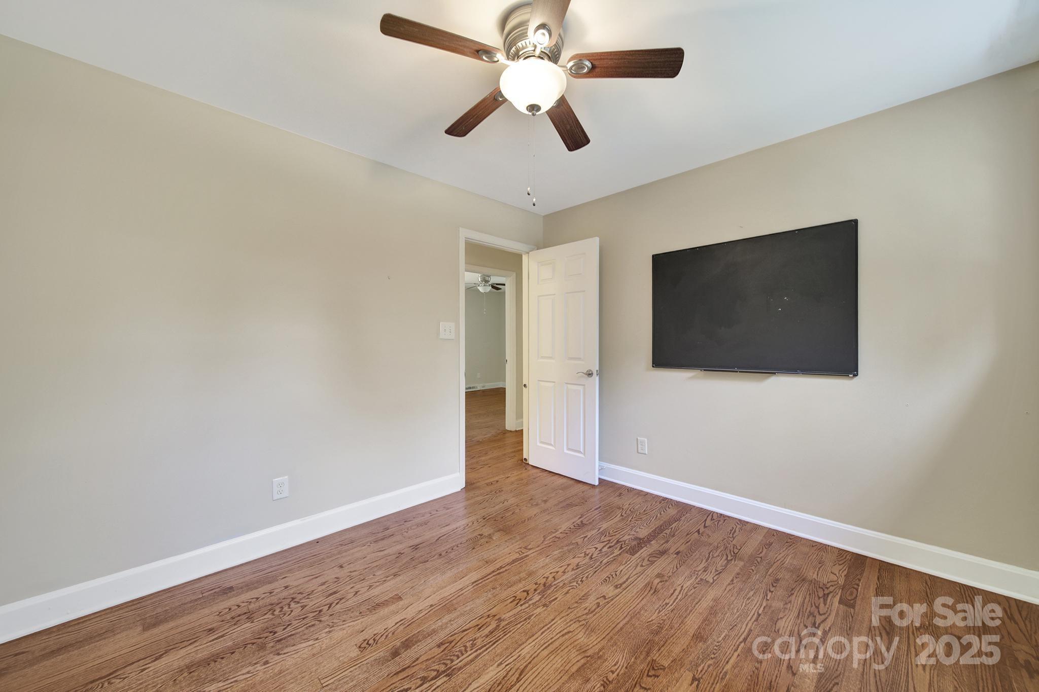 7424 Watercrest Road Charlotte, NC 28210 - Photo 13 of 32 a view of an empty room with wooden floor and a ceiling fan