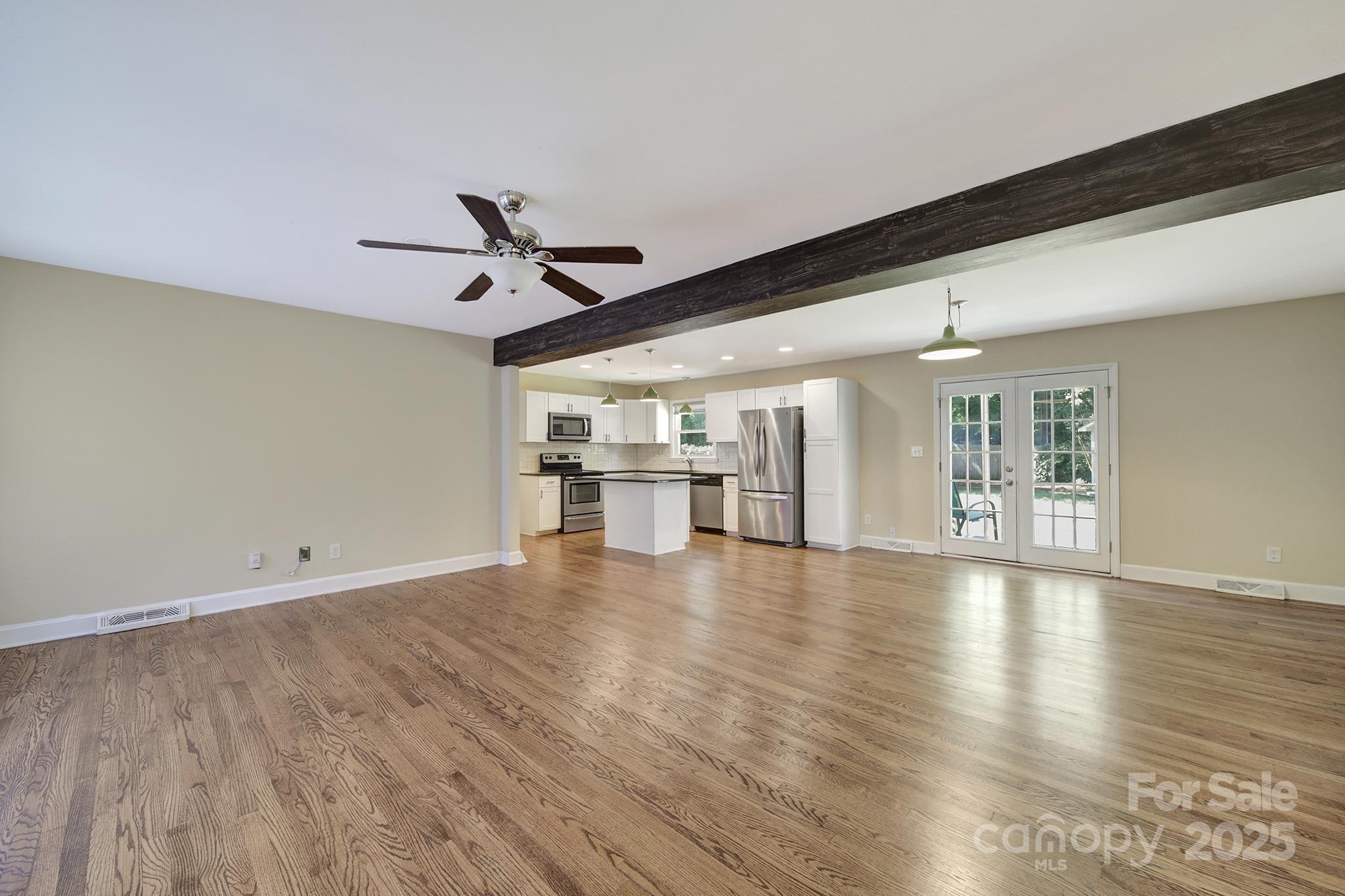 7424 Watercrest Road Charlotte, NC 28210 - Photo 3 of 32 a view of an empty room with wooden floor and a ceiling fan