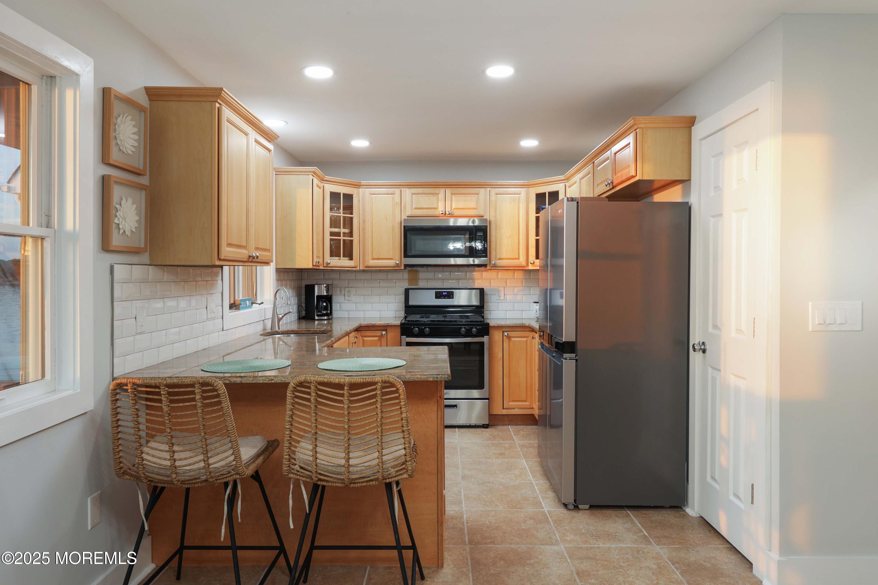 151 Shore Drive Brick, NJ 08723 - Photo 11 of 40 a kitchen with stainless steel appliances granite countertop a refrigerator a stove a sink a microwave and a dining table with wooden cabinet
